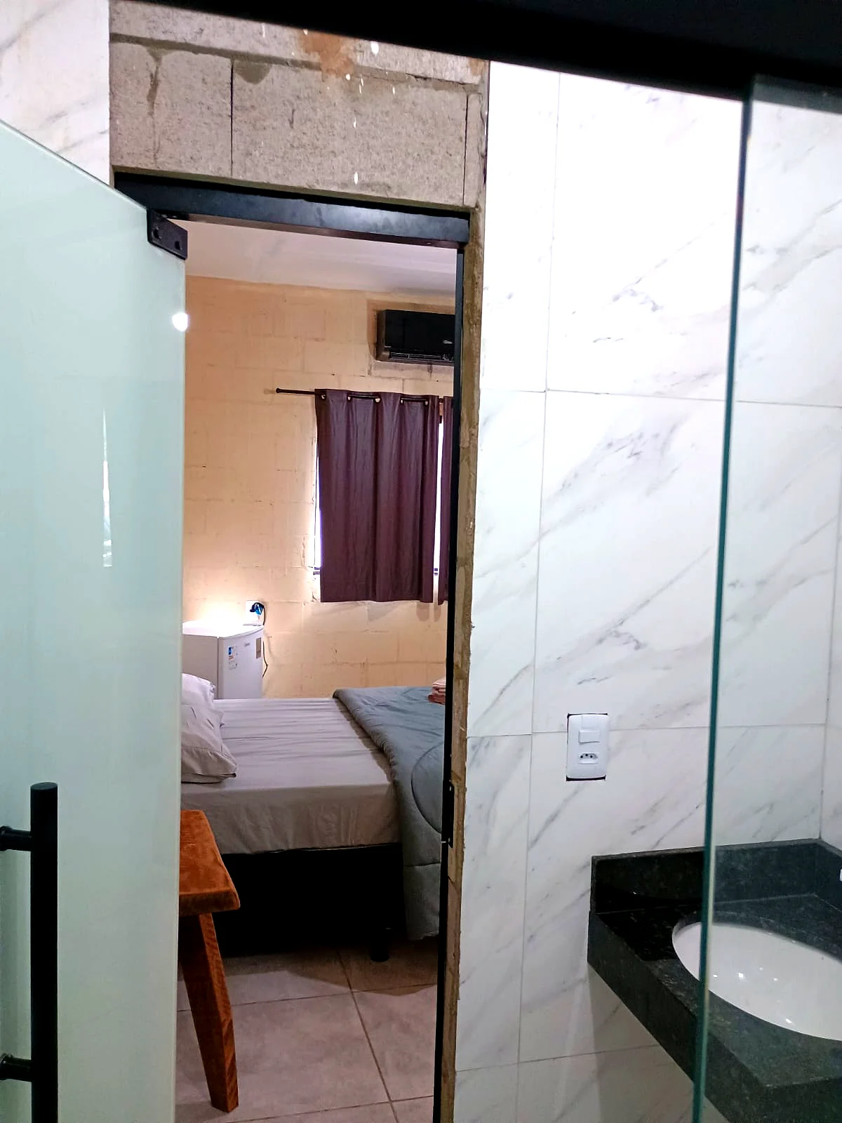 Vista da porta do banheiro para o quarto com revestimento mármore — Pousada Vale do Jamacá