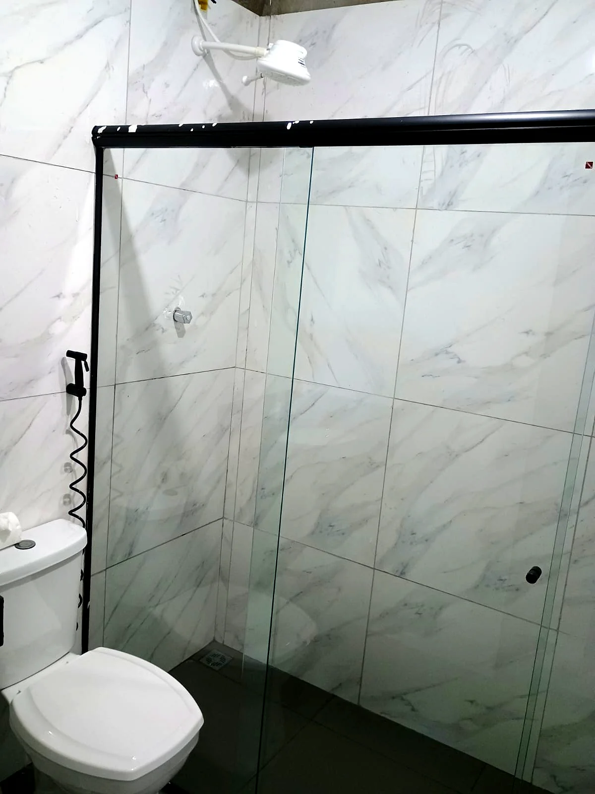 Banheiro com chuveiro, box de vidro e porcelanato mármore — Pousada Vale do Jamacá